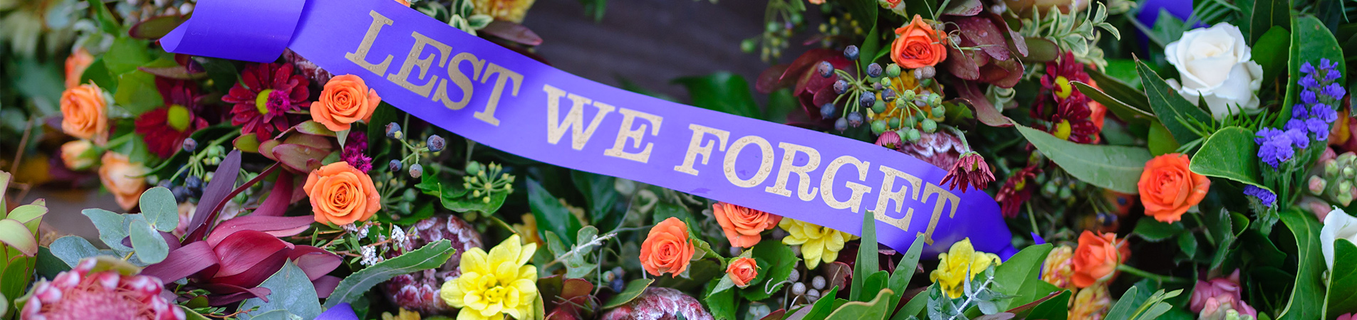 Image of a wreath with the words "Lest We Forget"