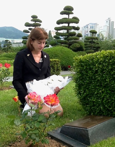 Louise Evans kneels at her uncle's grave in Pusan