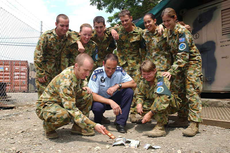 Image: Defence Australia |  hoto By Leading Seaman (LSPH) Ollie Garside Service people are practicing their two-up skills for Anzac Day in Honiara, Solomon Islands. 