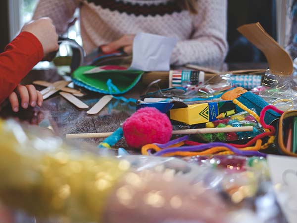 People sitting at a table covered in craft materials.