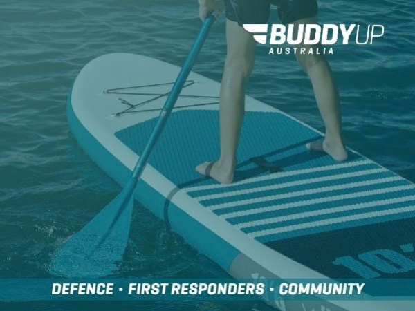 Paddle board on the water with a person on the board with the paddle resting in the water