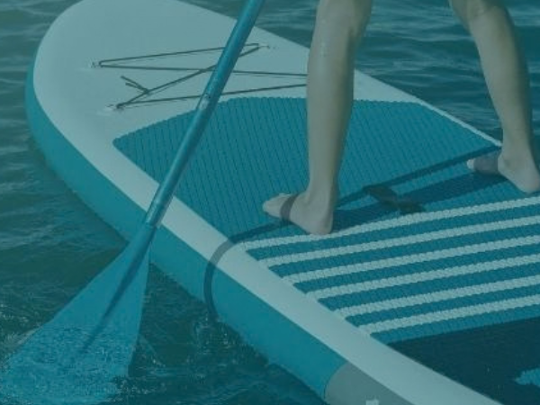 Paddle board on the water with a person on the board with the paddle resting in the water